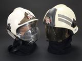 pair of firemen wearing helmets and goggles against a black background