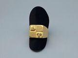 une bague en or posée sur un porte-bague noir, sur une surface blanche
