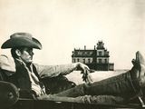 a black and white photo of a man in a cowboy hat sitting in a car