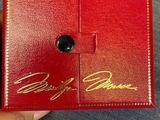 Quelqu'un tient une boîte rouge sur laquelle figure une inscription dorée.