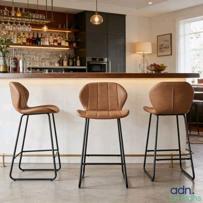 trois tabourets de bar en cuir marron sont disposés devant un bar
