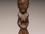 a wooden statue of a woman with a hat on her head
