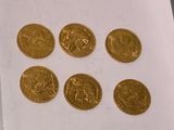 six gold coins are arranged in a row on a white surface