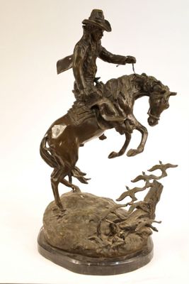 statue of a man on a horse with a dog on a rock