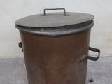 a large metal pot with a lid on a cement floor