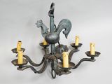 an image of a metal chandelier with five candles and a rooster