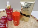 bottles of nuxe super serum and a packet of nuxe super serum sit on a wicker tray
