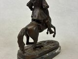 bronze statue of a man on a horse on a white background