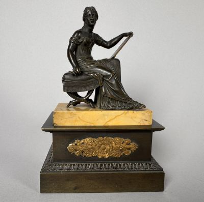 an antique bronze statue of a woman sitting on top of a marble base