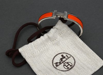 an orange and white bracelet with a silver buckle and a white pouch