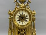 a gold clock with a bird on top of it