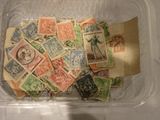 de nombreux timbres de toutes sortes dans une boîte en plastique posée sur une table