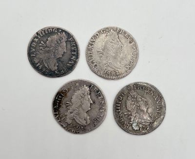 quatre types différents de pièces d'argent posées sur une surface blanche