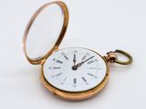 a gold pocket watch with a white face and roman numerals on it