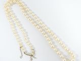 a close up of a white pearl necklace with a silver clasp