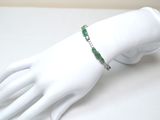 une main de mannequin blanche à laquelle est attaché un bracelet vert
