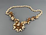 a close up of a necklace with shells on a gray surface