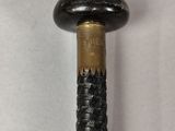 a close up of a black and gold cane on a white surface