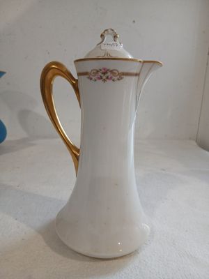 a white and gold coffee pot sitting on a table
