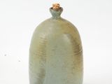 a small green vase with a brown top on a white surface