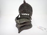 une vieille statue en bronze représentant une personne assise sur une chaise