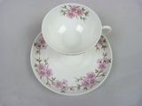 a white cup and saucer with pink flowers on it