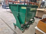 the large green dumpster is sitting in the warehouse on the floor