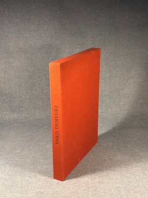 an orange book sitting on top of a table next to a gray wall