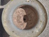 a cement bowl with a hole in it sitting on the ground