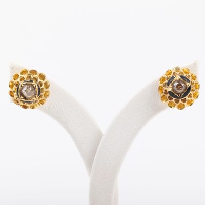 une paire de boucles d'oreilles en diamants jaunes et blancs, présentées sur un socle blanc