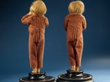 pair of antique dolls of a boy and a girl standing on pedestals