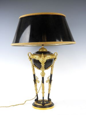 une image représentant une lampe noire et dorée, surmontée d'un abat-jour noir