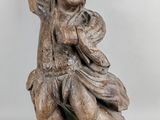 statue of a boy sitting on a tree branch holding a bag
