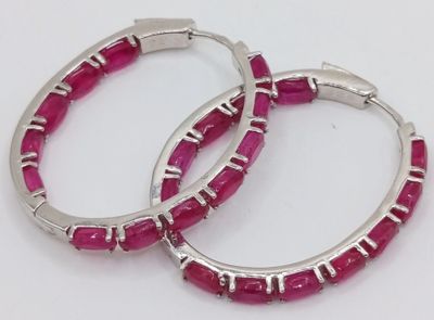 pair of silver hoop earrings with pink stones on white background