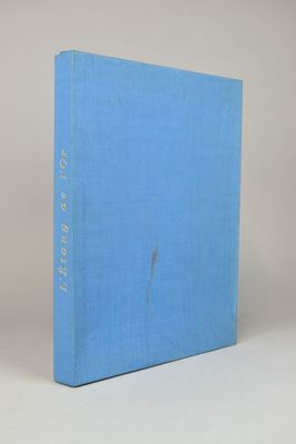 un livre bleu posé sur une table à côté d'un mur blanc
