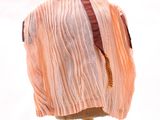 chemise plissée couleur pêche posée sur un mannequin, ornée d'un ruban rouge