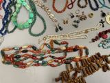 many different necklaces and bracelets laid out on a table