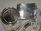 trois plateaux en argent et un miroir posés sur une table