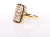 a close up of a gold ring with a diamond and blue sapphire