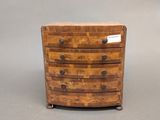 a small wooden chest of drawers with a label on it