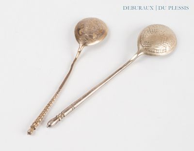 two silver spoons sitting next to each other on a white surface