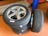 tires and rims are stacked on a pallet in a garage