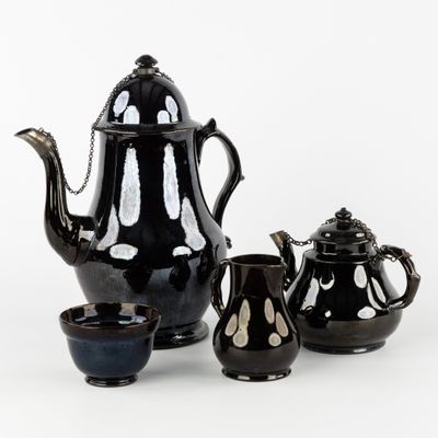 des théières et des tasses noires et blanches posées sur un fond blanc