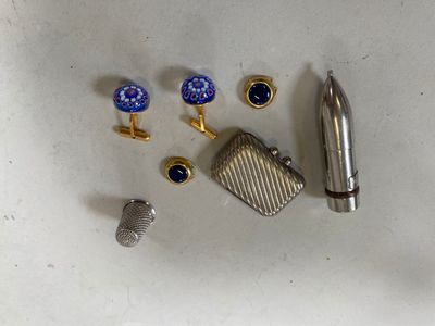 a silver lighter, cufflinks, and a lighter on a table