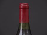 a bottle of wine with a red cap sitting on top of a table