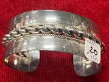 bracelet manchette en argent avec motif tressé et étiquette de prix sur un tissu rouge