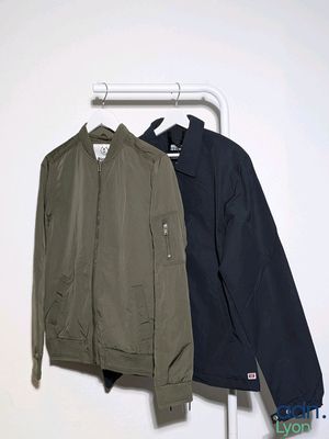 two jackets hanging on a clothes rack in a white room