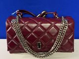a red handbag with a chain strap on a white table