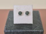 un gros plan sur une paire de boucles d'oreilles en pierre verte posées sur un bloc de marbre