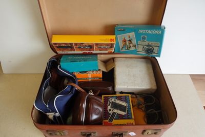 une valise remplie d'objets, posée par terre